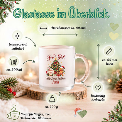 Infografik „Glastasse im Überblick“ zur personalisierten Weihnachtstasse mit dem Beispielnamen Anna und dem Motiv „Just a Girl Who Loves Christmas“. Pfeile zeigen die Maße und Eigenschaften: ca. 80 mm Durchmesser, 95 mm Höhe, 300 ml Fassungsvermögen und 400 g Gewicht. Das transparente, satinierte Glas ist beidseitig bedruckt und besitzt einen Henkel. Die Tasse steht auf einer Holzscheibe vor grünem Weihnachtshintergrund. Geeignet für Kaffee, Tee, Kakao oder Glühwein als Weihnachtsgeschenk mit Wunschname.