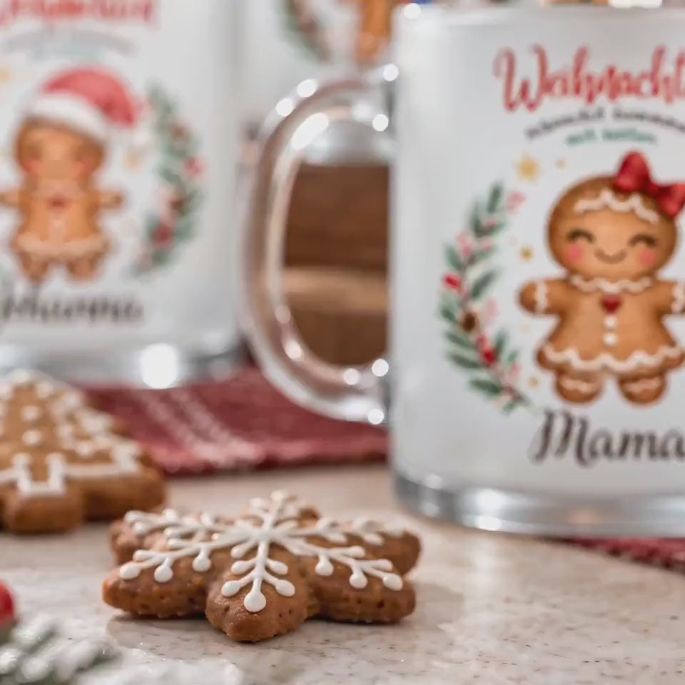 Produktvideo der personalisierten Weihnachtstassen mit Lebkuchenfiguren und Wunschbeschriftung, arrangiert zwischen Weihnachtsdekoration und Plätzchen. Die Lebkuchenmotive sind von einem Tannenkranz mit Zapfen, Beeren und goldenen Sternen umrahmt und tragen „Weihnachten schmeckt zusammen am besten“. Die satinierte 300-ml-Glastasse wird beidseitig mit Wunschname bedruckt. Persönliches Weihnachtsgeschenk für Familie, Freunde oder Kollegen, auch zu Nikolaus oder zum Wichteln. Für Kaffee, Tee und Kakao.